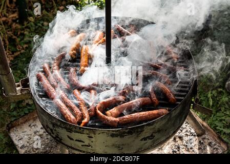 Bollitore Charcoal barbecue Grill in giardino o cortile. Salsicce alla griglia con molto fumo. Griglia per barbecue portatile per la cottura alla griglia all'aperto Foto Stock