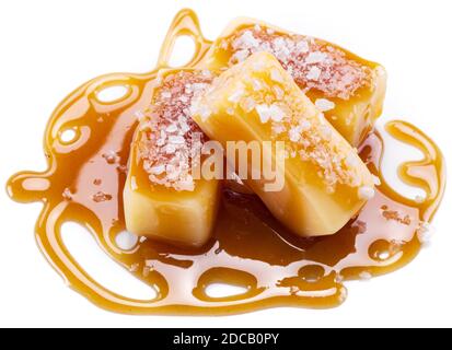 Caramelle al caramello salate ricoperte di caramello allo zucchero fuso isolato su fondo bianco. Foto Stock