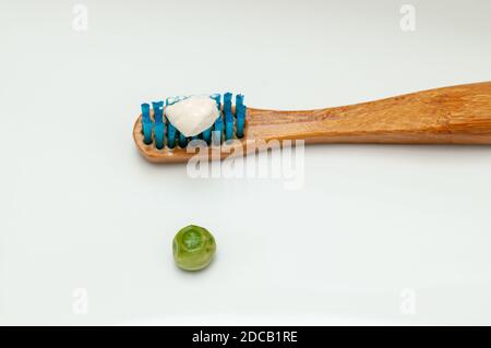 Un primo piano di uno spazzolino da denti in legno con il consigliato dentifricio Foto Stock