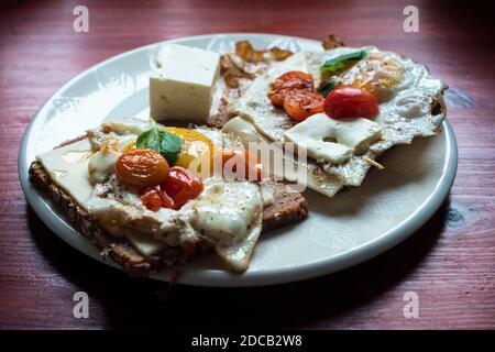 Uova fritte con pomodori e basilico, stile mediterraneo Foto Stock