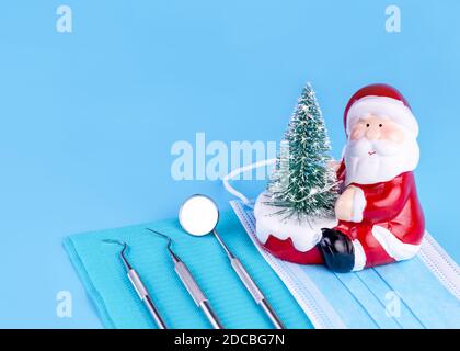 Buon Natale e Felice anno nuovo da Dentist Set di Dental Tools e Babbo Natale su sfondo blu. Foto Stock