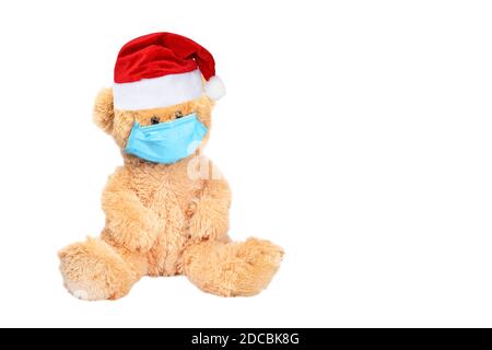 Orsacchiotto indossare PP non tessuto maschera medica monouso e rosso Natale o Babbo Natale cappello isolato su sfondo bianco. Arrestare Coronavirus e Air Foto Stock