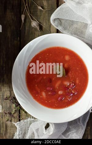 Pasto proteico vegano con fagioli rossi e salsa di pomodoro in ciotola bianca piatta su un tavolo rustico, dall'alto, vista dall'alto, cibo vegetariano concetto Foto Stock