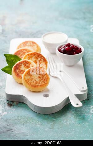 Frittelle al formaggio Russo scirniki con confettura di mirtilli e yogurt, fuoco selettivo Foto Stock