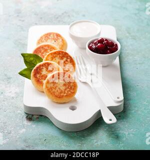 Frittelle al formaggio Russo scirniki con confettura di mirtilli e yogurt, fuoco selettivo Foto Stock