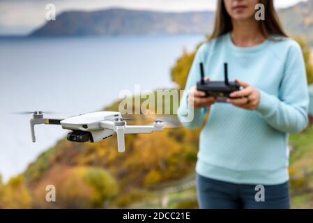 Figura sfocata di ragazza controlla un drone su sfondo sfocato autunno. Confetto messa a fuoco morbida Foto Stock