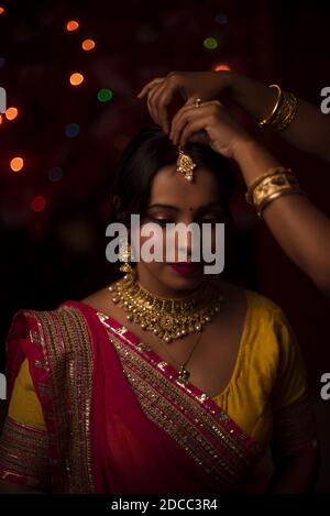 Ritratto di una bella bruna indiana bengalese davanti dello sfondo colorato e chiaro bokeh creato da una piccola catena luci la sera di Foto Stock