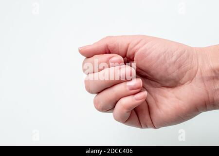 Concetto per unghie naturali, unghie grezze. Primo piano della mano caucasica femminile con unghie naturali non lucidate, cuticola in crescita su sfondo bianco, vista dall'alto Foto Stock