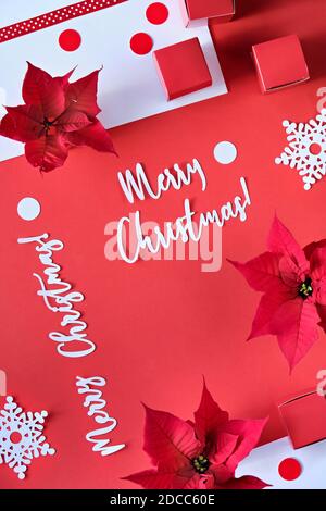 Texte sur Buon Natale. Poinsettia, fiocchi di neve, confetti di carta bianca rossa. Vista dall'alto, design monocromatico. Foto Stock