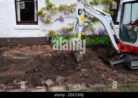 mini digger che lavora in giardino facendo patio Foto Stock