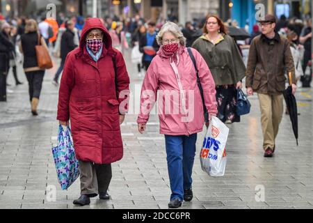 Gli acquirenti che indossano maschere facciali portano borse nel centro di Cardiff, dove i negozi sono aperti e le persone sono fuori in numero che approfittano dell'acquisto di articoli non essenziali in vista di Natale. Le restrizioni in tutto il Galles sono state rilassate a seguito di un blocco di due settimane di "firewbreak". Foto Stock