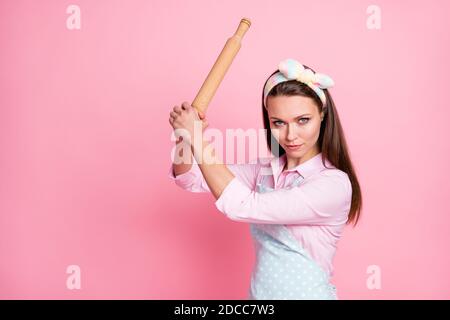 Primo piano ritratto di lei bella attraente pericoloso arrabbiato serio casalinga che tiene nelle mani il perno di rotolamento di legno minacciando i diritti di combattimento Foto Stock