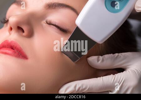 Estetista fa ultrasuoni pulizia del viso. Cosmetologia hardware. Primo piano della foto. Foto Stock