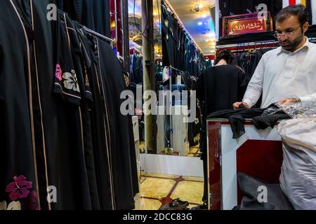 Un uomo arabo che vende abiti in un negozio di tessuti tradizionali arabi Hijab nella Gold Street, Gold Souk, a Dubai, Emirati Arabi Uniti. Foto Stock