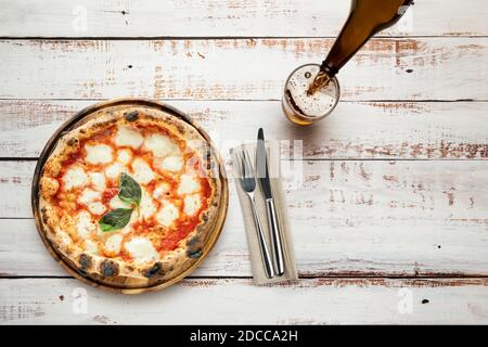 Vista dall'alto della pizza su taglieri in legno con posate e birra Foto Stock