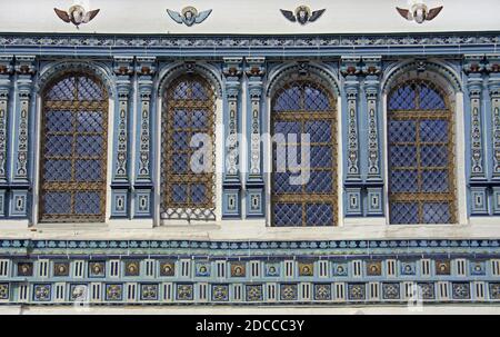 Vecchie finestre ad arco con bella piastrella ornamentale colorata su un muro di mattoni bianchi della chiesa cristiana Foto Stock