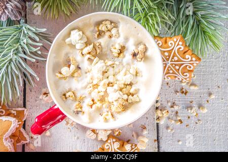 Tazza di caffè popcorn latte. Bevanda calda alla moda, latte con popcorn al formaggio salato, con decorazione natalizia invernale, spazio copia di sfondo in legno bianco Foto Stock