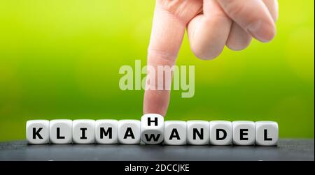 Simbolo di un sistema di scambio delle emissioni. La mano trasforma i dadi e cambia la parola tedesca 'Klimawandel' (cambiamento climatico) in 'Klimahandell' (commercio climatico). Foto Stock