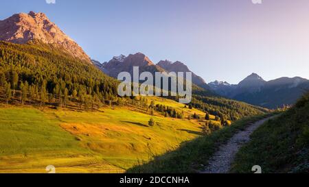 Il sole tramonta sulle montagne che circondano Tarasp, un villaggio di Graubünden, in Svizzera. Si trova all'interno della bassa valle dell'Engadin lungo la Foto Stock