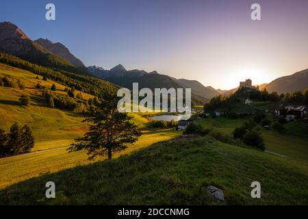 Il sole sorge sulle montagne che circondano Tarasp e il suo castello, nel cantone di Graubünden (Engadin) Svizzera. Foto Stock