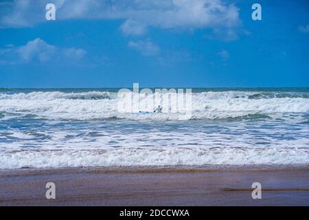 Solitario surfer in un mare tempestoso su una tavola a cavallo di un wave.Bude, Cornovaglia UK 6 luglio 2020 Foto Stock