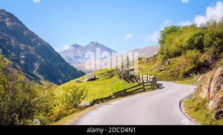 Una strada solitaria in salita e campi verdi vicino al villaggio di Vent nel Ötztal (Tirolo, Austria), circondato da montagne Foto Stock