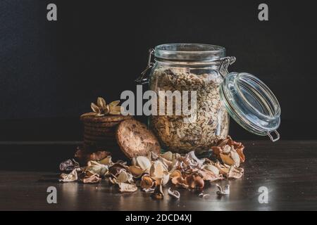 Serve una sana colazione mattutina con muesli a grani interi a fiocchi di mais E pile di deliziosi biscotti fatti in casa al cioccolato con chip su un sfondo scuro d'epoca Foto Stock