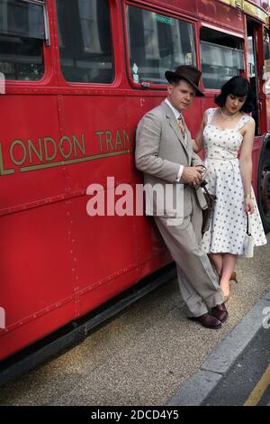 GRAN BRETAGNA / Inghilterra /Londra / CHAP Olympiad/ coppia in abiti vintage in posa davanti all'iconico London Bus. Foto Stock