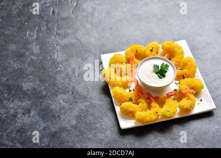 Gamberi fritti con salsa sulla piastra bianca su pietra blu sfondo con testo libero spazio. Foto Stock