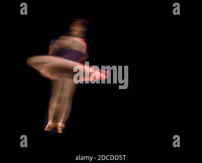 Ballerina classica sul palcoscenico scuro, che rotola con effetto di sfocatura del movimento. Composizione astratta. Foto Stock