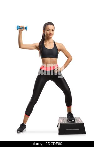 Ritratto a lunghezza intera di una giovane femmina in esercizio sportivo step aerobico con un dumbbell isolato su sfondo bianco Foto Stock