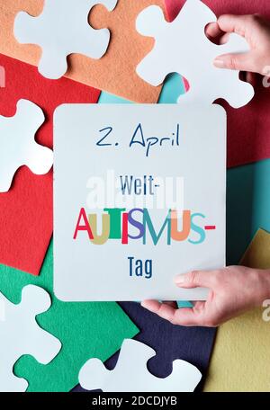 Hands Hold pagina con testo in tedesco significa 2 aprile Autism giornata mondiale di consapevolezza. Elementi puzzle Foto Stock