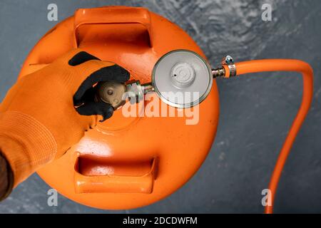 Svitando la bombola di propano-butano. Gas combustibile utilizzato nelle abitazioni. Sfondo scuro. Foto Stock