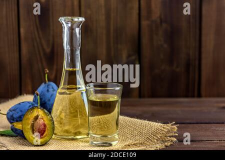 Brandy di prugne o schnapps in bicchieri e prugne fresche gustose su un tavolo di legno con spazio di copia per il testo. Messa a fuoco selettiva. Foto Stock
