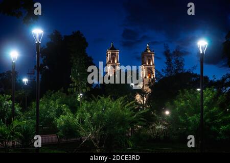 Parco nella piazza principale 'Francisco Canton Rosado' con le torri della chiesa coloniale di San Servacio di notte nel centro di Valladolid, Yucatan, Messico Foto Stock