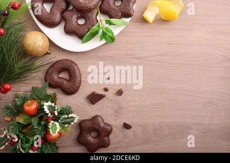 Biscotti ricoperti di cioccolato su una panca di legno con decorazioni natalizie. Vista dall'alto. Composizione orizzontale. Foto Stock