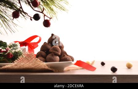 Centrotavola decorativa natalizia su base in legno con piatto pieno di tartufi al cioccolato con fondo bianco isolato. Vista frontale. Composti orizzontali Foto Stock