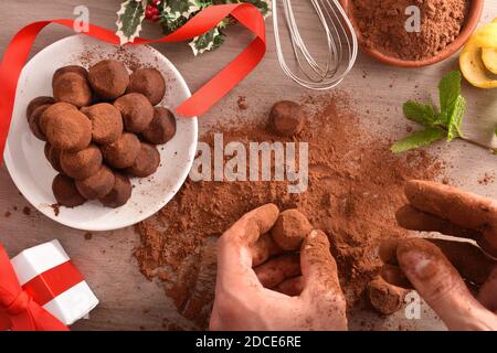 Produzione di tartufi di cioccolato per dolci caramelle a casa per un evento su una panca di legno. Vista dall'alto. Composizione orizzontale. Foto Stock