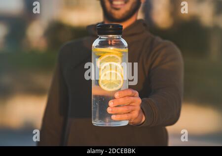 Uomo con bottiglia di acqua dolce al limone. Bevande sane, dieta e concetto di detox Foto Stock