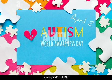 Design creativo per Autism World Day, 2 aprile. Banner panoramico di consapevolezza, le mani tengono il cuore rosso. Foto Stock