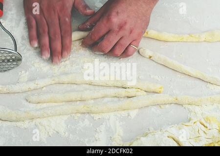 Preparazione dell'impasto con le mani in panetteria o a casa/ chiusura delle mani dello chef uomo preparazione dell'impasto sul tavolo, in polvere con la farina. Foto Stock