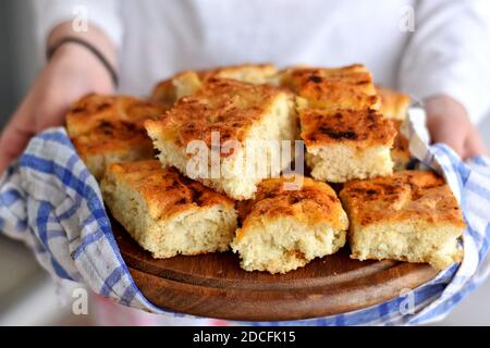 Mani femminili che tengono pane appena sfornato/ focaccia italiana fatta in casa con rosmarino e olio d'oliva/ appena sfornata e pronta a mangiare Foto Stock