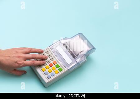 Primo piano della mano della donna premendo i pulsanti del registratore di cassa su sfondo blu, vista dall'alto, spazio di copia. Concetto di business, commercio e shopping Foto Stock