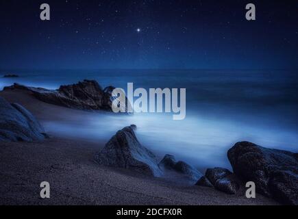 Notte romantica stellata Fotografia con cielo blu profondo alla spiaggia di Sant Pol de Mar, Catalunya, Spagna Foto Stock