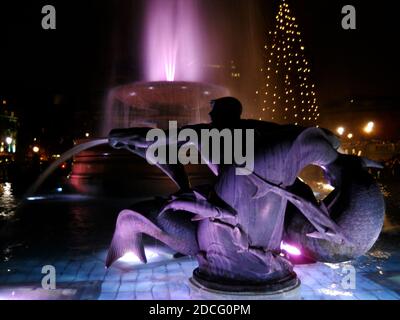 Vista notturna di Trafalgar Square, Londra, con un albero di Natale, regalato dalla Norvegia, sullo sfondo e la fontana in primo piano del Memoriale dell'ellicoe Foto Stock