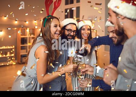 Felici amici sorridenti che versano champagne in bottiglia e festeggiano il Natale a casa Foto Stock