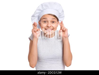 Teen girl in cappello chef, tenendo le dita incrociate e facendo desiderio, isolato su sfondo bianco. Foto Stock