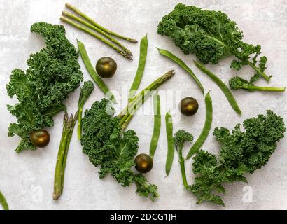 Una sana distribuzione di verdure fresche verdi crude: Broccolini, kale, piselli, fagioli, lattuga, pomodori. Foto Stock