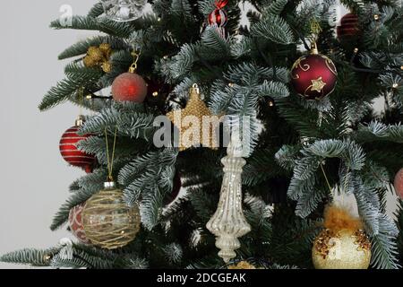 Decorazioni natalizie su un albero della casa. Le decorazioni rosse e dorate per le vacanze pendono dall'albero. Foto Stock