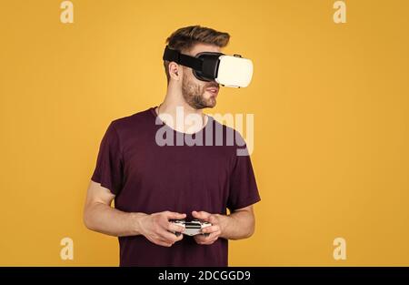 Nuova realtà. Giocatore di gioco con console. Maschio in visore VR. I giocatori felici usano la tecnologia moderna. Futuro digitale e innovazione. Realtà visiva. Uomo in occhiali VR wireless. Ragazzo gioca ai videogiochi. Foto Stock